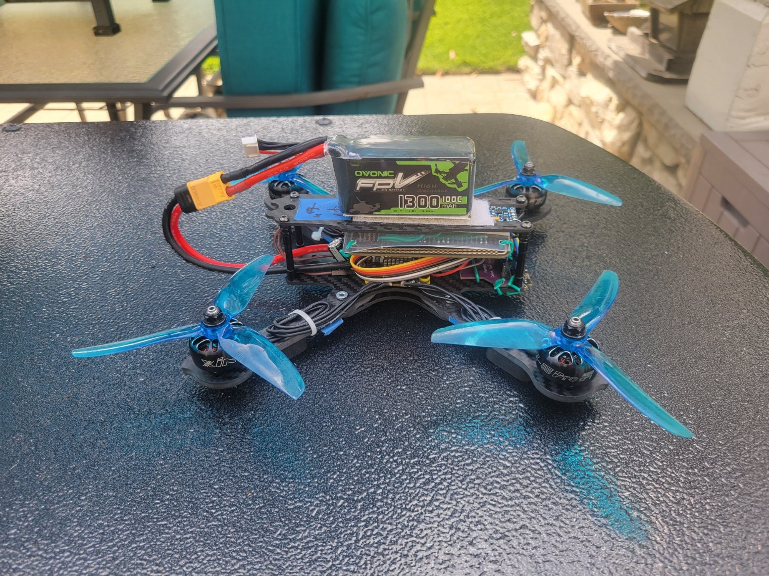 Side view of the custom 232 mm quadrotor showing its stacked deck layout, battery, and tri-blade propellers.
